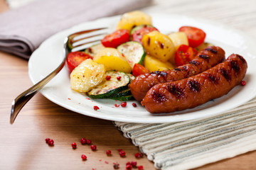 Grilled sausage with grilled vegetables on kitchen table