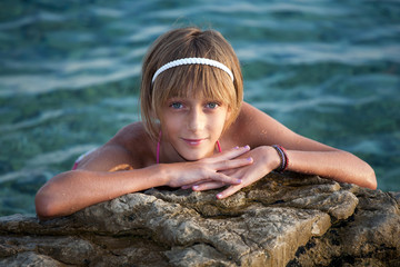 Teenage girl relaxing on a rock near the sea