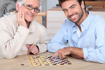 Fototapeta premium Young man playing game with elderly woman