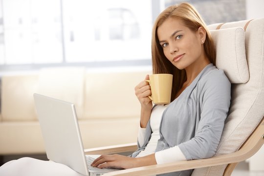 Pretty woman using laptop having tea