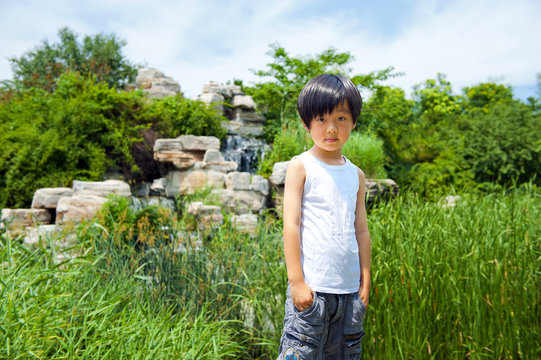 Cute Chinese boy outdoor in white shirt (in front of waterfall)