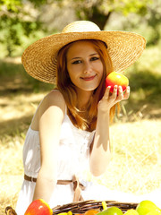 Beautiful redhead girl with fruits in basket at garden.