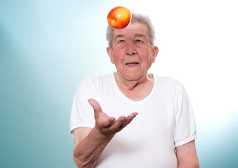 Senior wirft einen Apfel in die luft