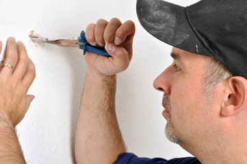 Handwerker zieht Dübel aus Wand