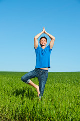Fototapeta na wymiar healthy young man doing yoga against sky