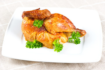 grilled chicken decorated with green parsley on white plate