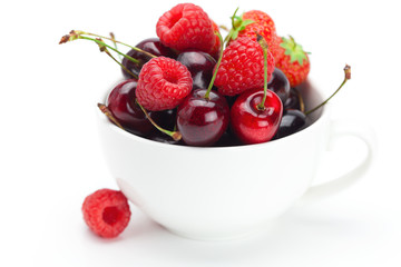raspberries, strawberries and cherries in a bowl isolated on whi