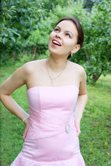 Young woman in pink dress near trees