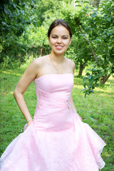 Young woman in pink dress near trees