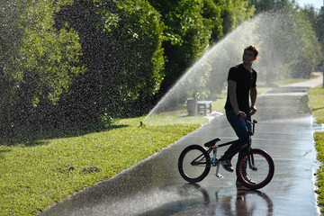 boy with bmx stay on fountain splashes background