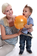 a mother and her little son playing with a balloon