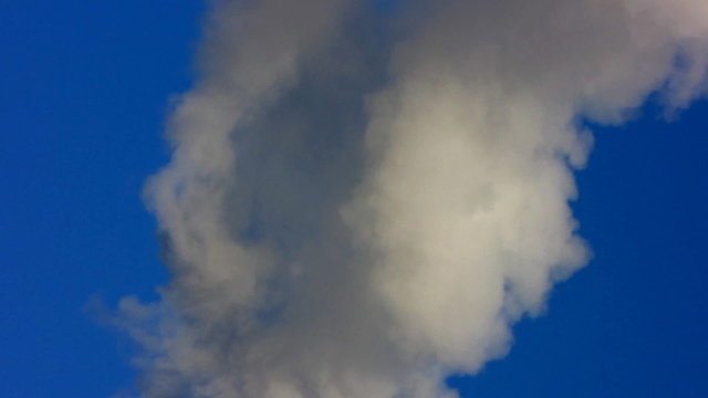 Smoke from a pipe on a background of the light-blue sky.