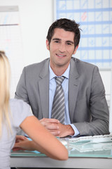 Man in suit sitting across a desk from a young woman