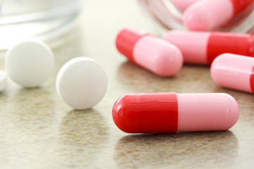 Close up of red and pink pills spilled from bottle