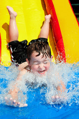 Young boy splashes into pool after going down water slide