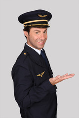 Male airline pilot smiling holding hand out © auremar