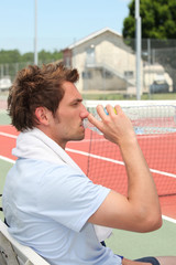 Tennis player drinking on the bench