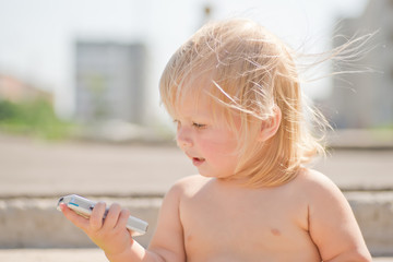 Adorable baby play with cell phone calling sitting on stairs on