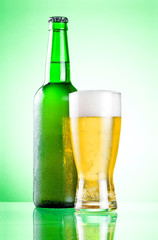 Chilled green bottle with condensate and a glass of beer lager o