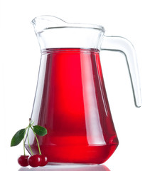 Jug of juice and three ripe cherries with leaves on white backgr