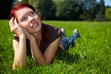 Verträumte Frau liegt im Gras