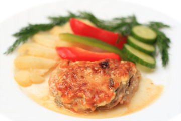 Piece of meat with vegetables on a white plate