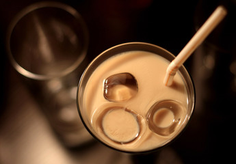 The cocktail is poured in a glass with ice and a straw