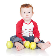 Baby boy sitting with green apples