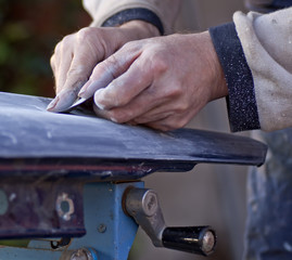 Obraz premium Handwerker schleift ein blaues Autoteil von Hand mit Schleifpapier