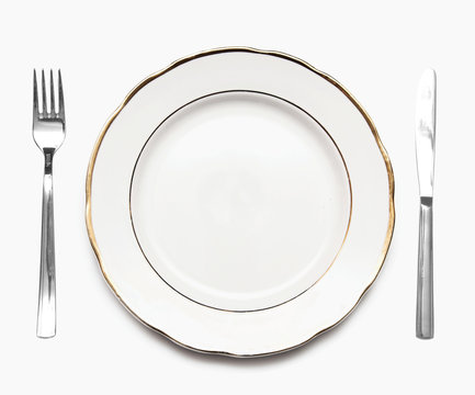 Knife, white plate and fork on a white background