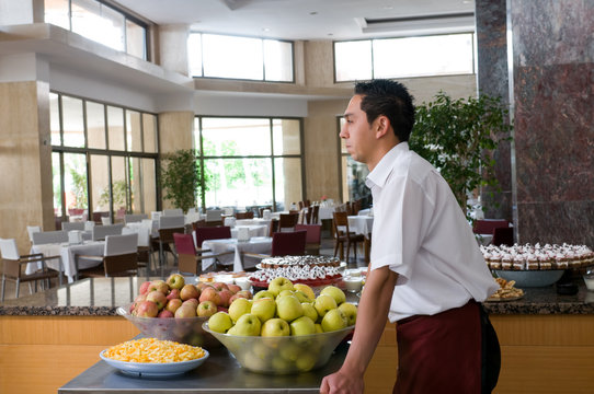 Waiter serving fresh fruits at restaurant.