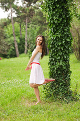 beautiful young woman is leaning against a tree