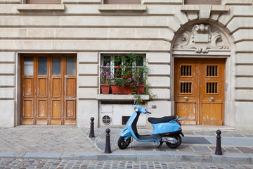 Blue retro moped parked near house on European cobblestone stree