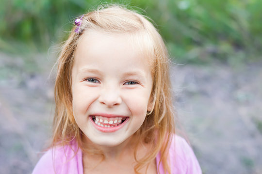 close up portrait of laughing blonde little girl outdoors in sum