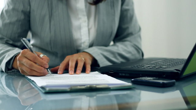 Businesswoman hands signing documents on reflective table