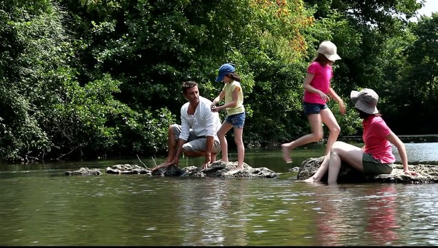 Family sitting in river in summer