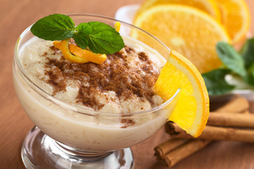 Rice pudding with cinnamon, orange slices and mint leaf