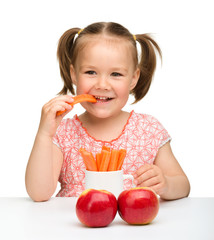 Cute little girl eats carrot and apples