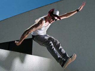 tattooed male parkour free runner jumping off a building