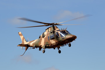 A camouflaged military helicopter in flight