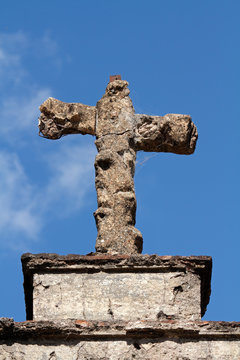 Old, weathered tomb stone cross against a blue sky