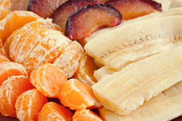 Mandarine, banana and blumbs, closeup.