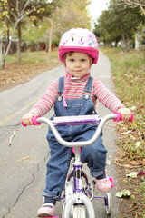 Fototapeta na wymiar Little girl on a bicycle with a helmet