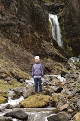 Frau steht vor einem natürlichen Wasserfall in Island