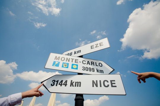 Two hands are pointing at traffic signs