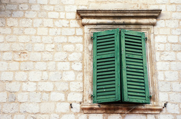 Fototapeta na wymiar Window with green shutters in old wall (Italia)