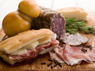 focaccia with ham salami and cheese over cutting board