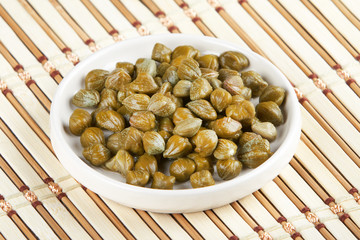 Pickled capers on white saucer