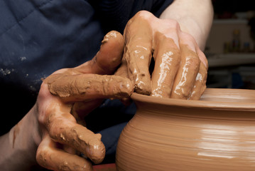 hands of a potter, creating an earthen jar on the circle