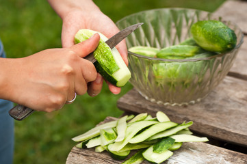 An image of hands pealing a cucumber in the yard